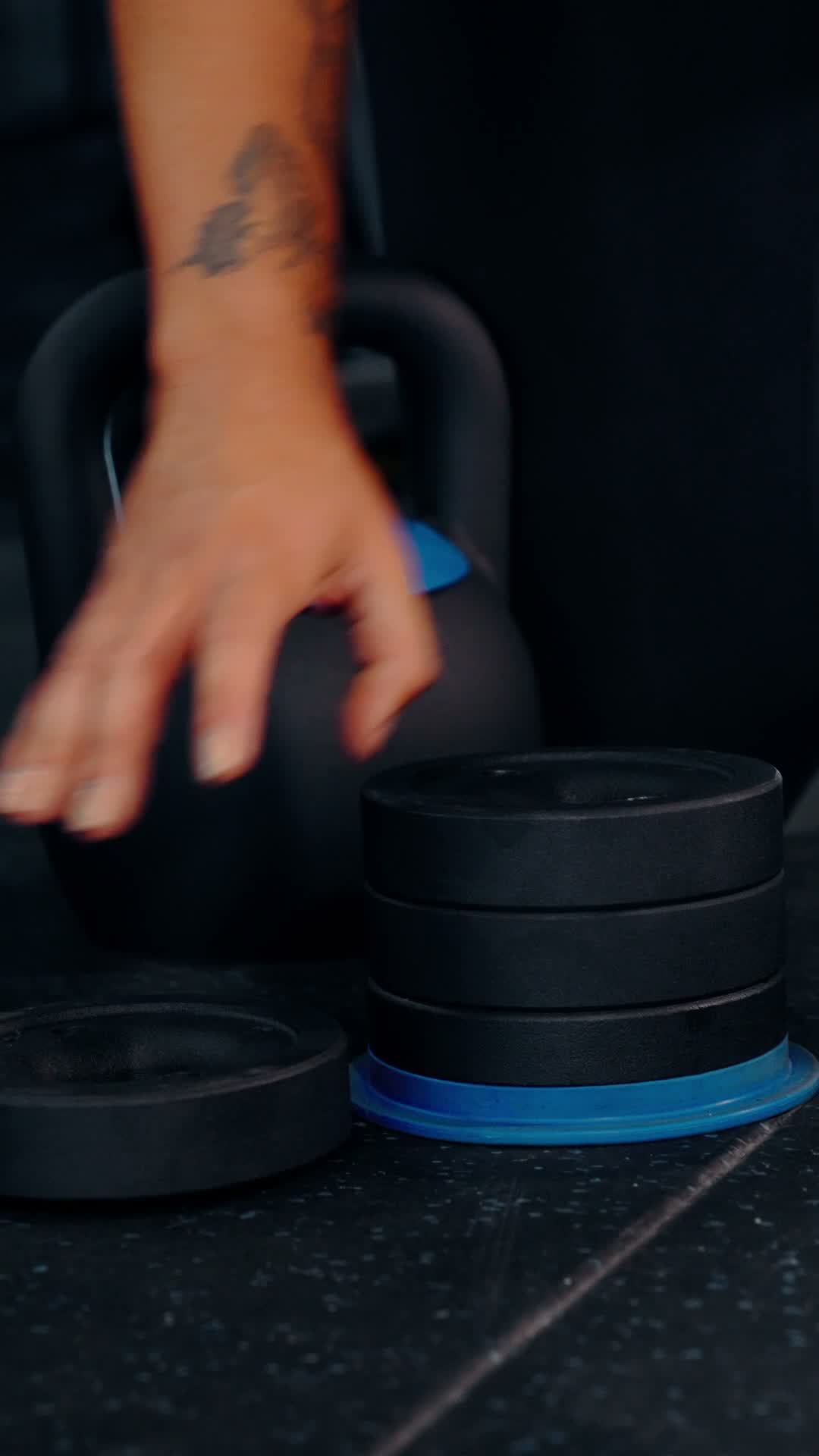 Hands stacking weight plates and locking the kettlebell shell over them